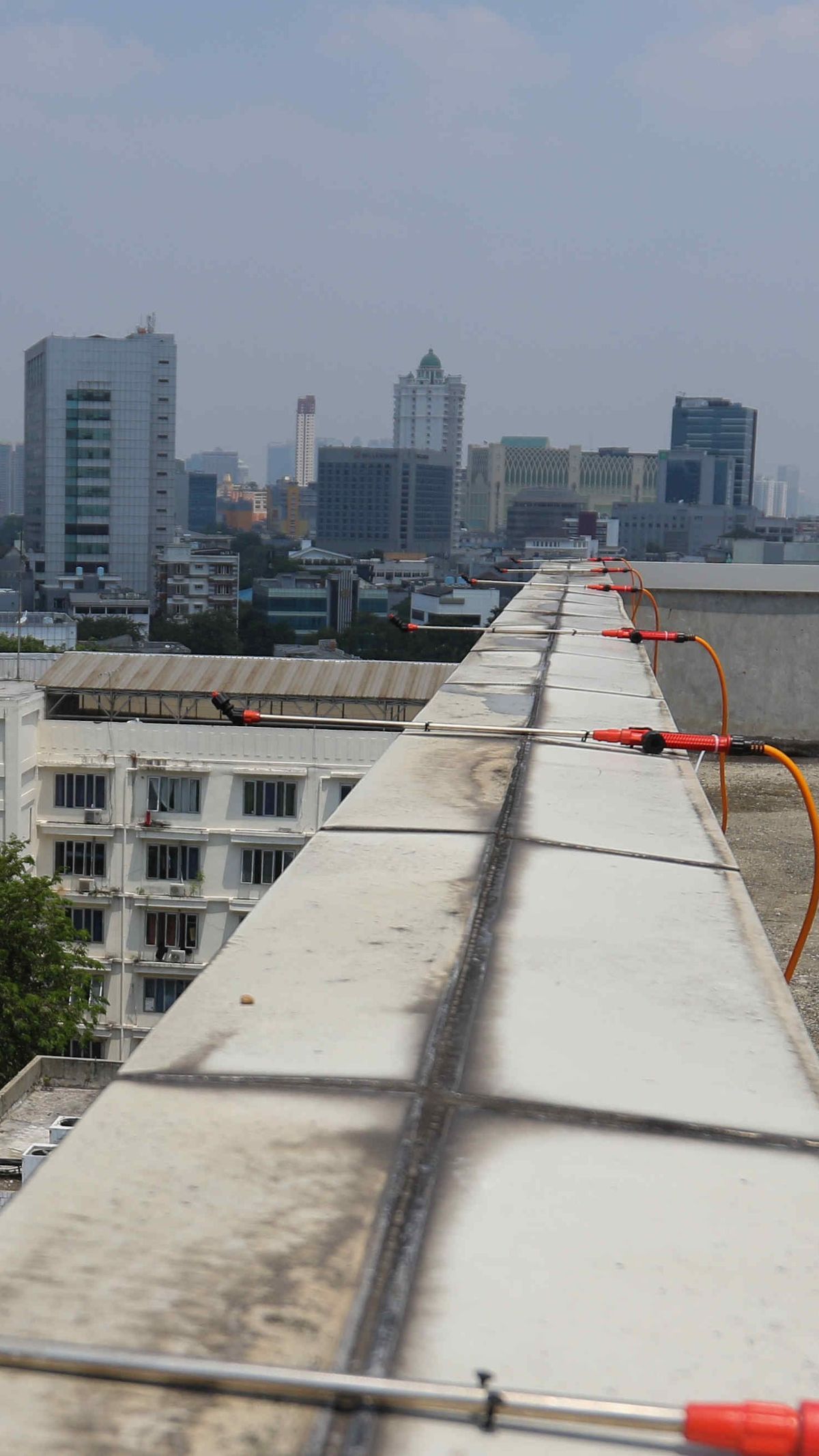 FOTO: Menyemprot Air dari Atap Gedung Jadi Solusi Kurangi Polusi Udara di Jakarta