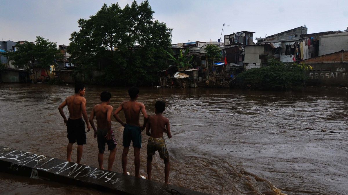 FOTO: Berbahaya! Aksi Nekat Anak-Anak Bermain di Tengah Derasnya Arus Kali Ciliwung