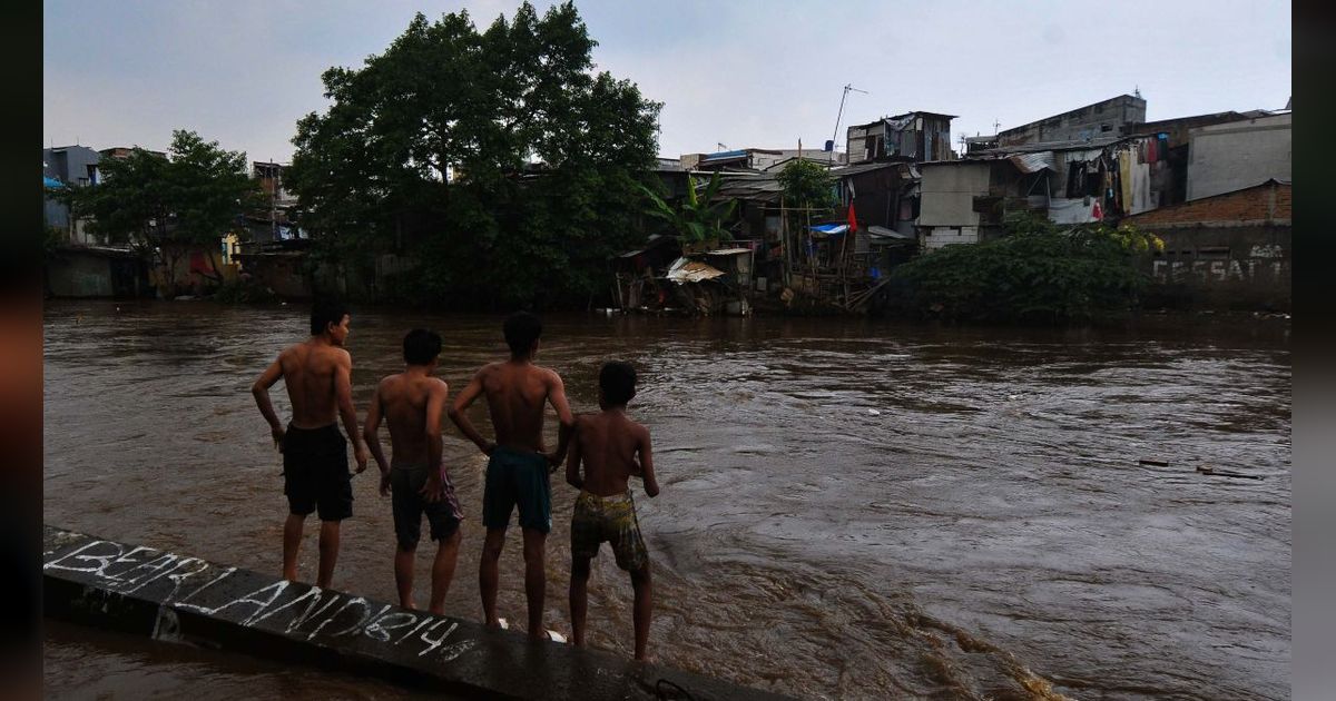 FOTO: Berbahaya! Aksi Nekat Anak-Anak Bermain di Tengah Derasnya Arus Kali Ciliwung