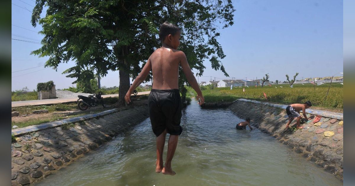 FOTO: Suhu di Bekasi Menyengat, Anak-Anak Asyik Main Air di Saluran Irigasi