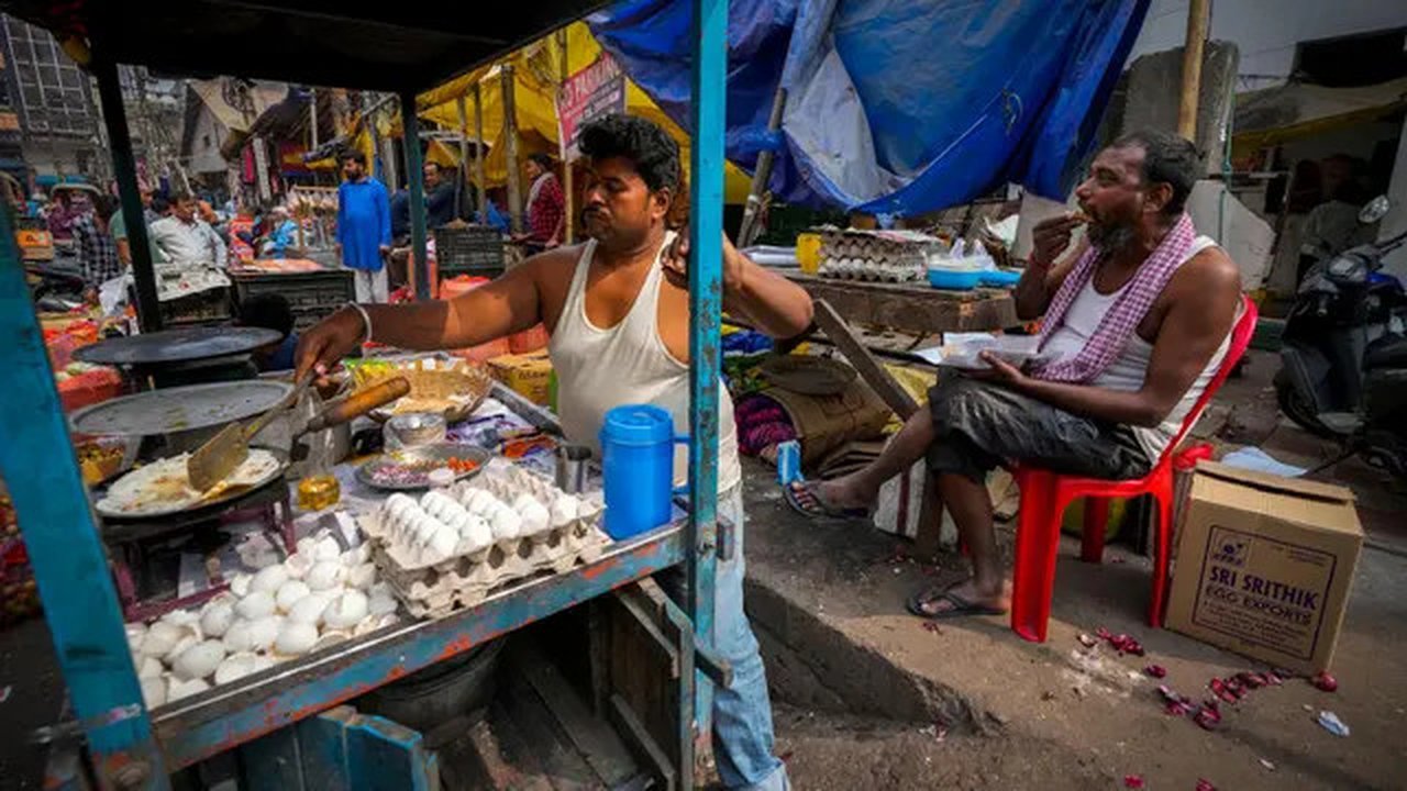 Seorang pedagang kaki lima menyiapkan makanan saat seorang pria makan di sebuah pasar grosir sayuran di Guwahati, India, Rabu (1/2/2023). Pemerintah Perdana Menteri India Narendra Modi mening