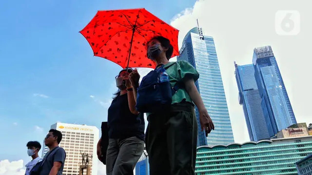 Warga menggunakan payung saat berjalan di tengah cuaca terik di kawasan Bundaran HI, Jakarta, Senin (24/4/2023). Badan Meteorologi Klimatologi dan Geofisika (BMKG) menyampaikan dinamika atmos