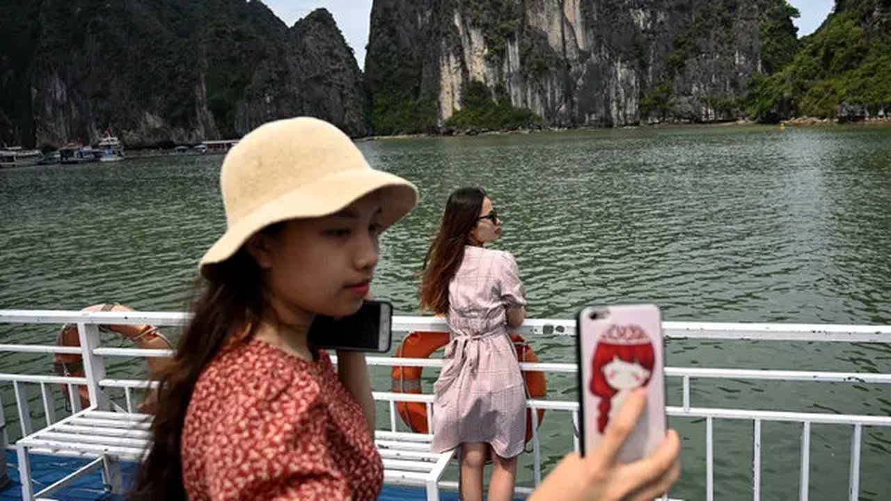 Wisatawan domestik berpose untuk foto di atas kapal di tengah Ha Long Bay, Quang Ninh, Vietnam, (16/5/2020). Sempat terpukul akibat pandemi virus corona Covid-19, pariwisata Vietnam kembali m