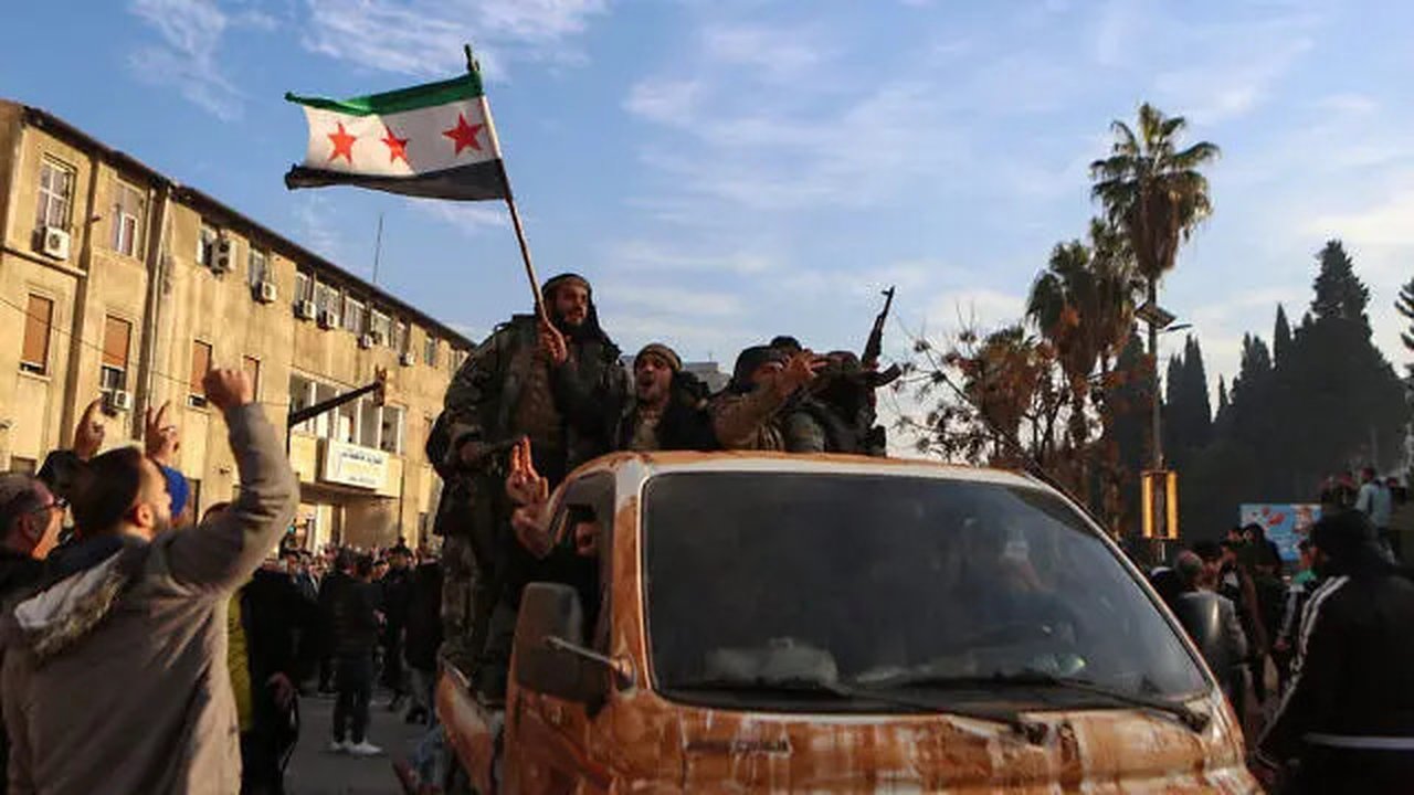 Kelompok pemberontak Suriah merayakan kemenangan di dekat Menara Jam di Homs pada Minggu (8/12/2024), setelah pasukan pemberontak memasuki kota ketiga Suriah pada malam hari. (Aaref WATAD / A