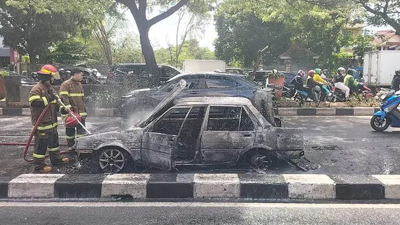 Petugas DPKP Kota Depok memadamkan api yang membakar mobil di Jalan Raya Margonda. Kebakaran diduga dipicu korsleting listrik. (Liputan6.com/Dicky Agung Prihanto)