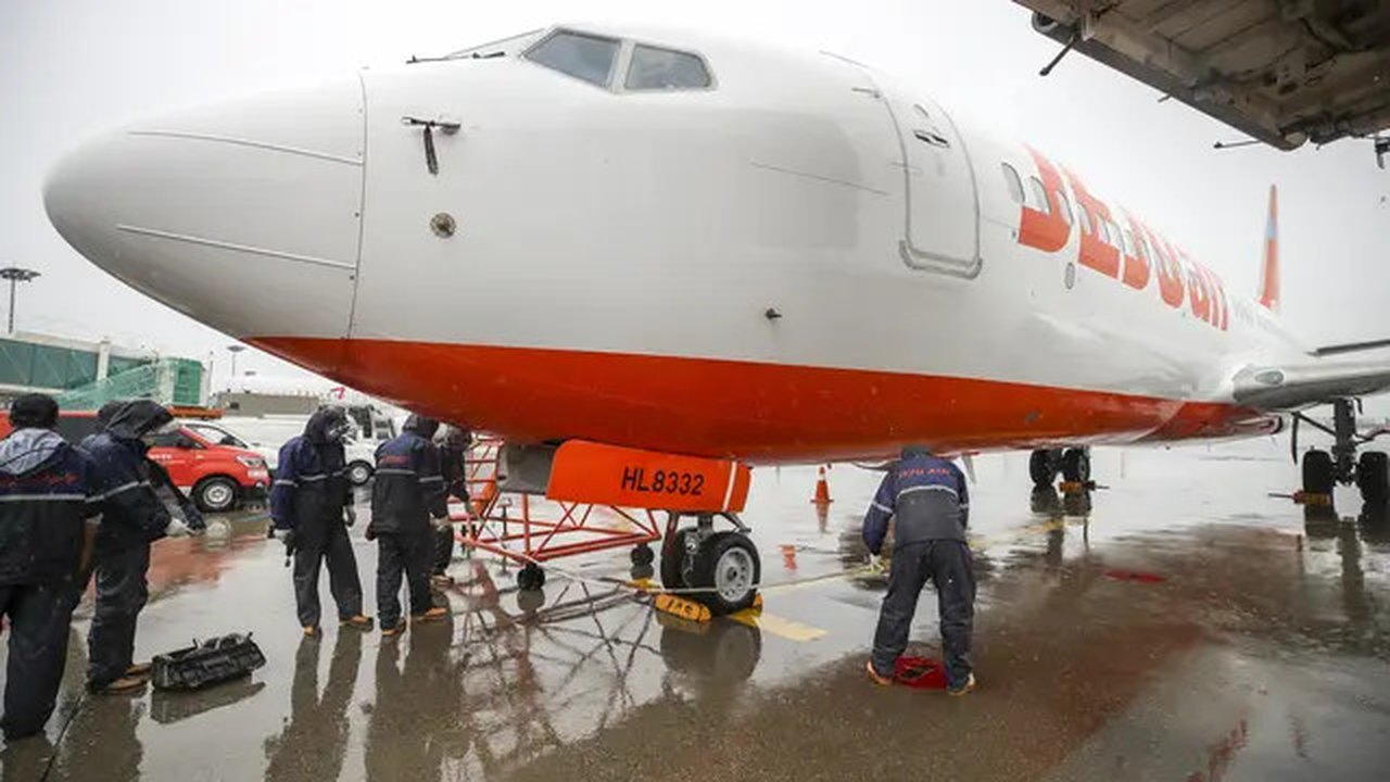 Mekanik maskapai Jeju Air mengikat sebuah pesawat di landasan saat Topan Hinnamnor bergerak menuju Semenanjung Korea di Bandara Internasional Gimpo di Seoul, Korea Selatan, Senin (5/9/2022