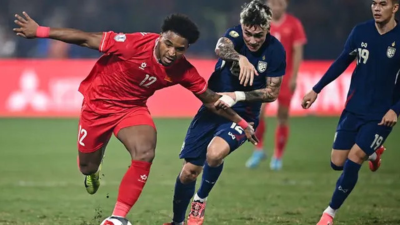 Pemain naturalisasi baru Vietnam, Nguyen Xuan Son (kiri) menggiring bola melewati pemain Thailand, Nicholas Mickelson dalam laga leg pertama final Piala AFF 2024 yang berlangsung di Viet T