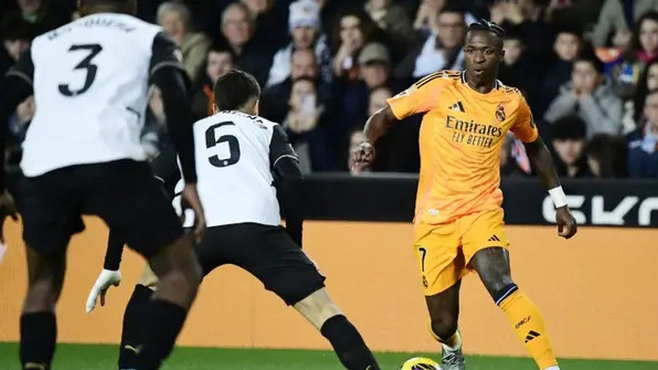 Pemain depan Real Madrid asal Brasil #7, Vinicius Junior (kanan), mencoba menggiring bola melewati gelandang Valencia asal Argentina #05, Enzo Barrenechea (tengah), selama pertanding