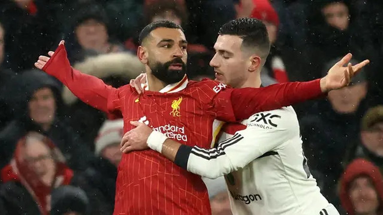 Pemain Liverpool, Mohamed Salah tampak diadang pemain MU Diogo Dalot. (Darren Staples / AFP)