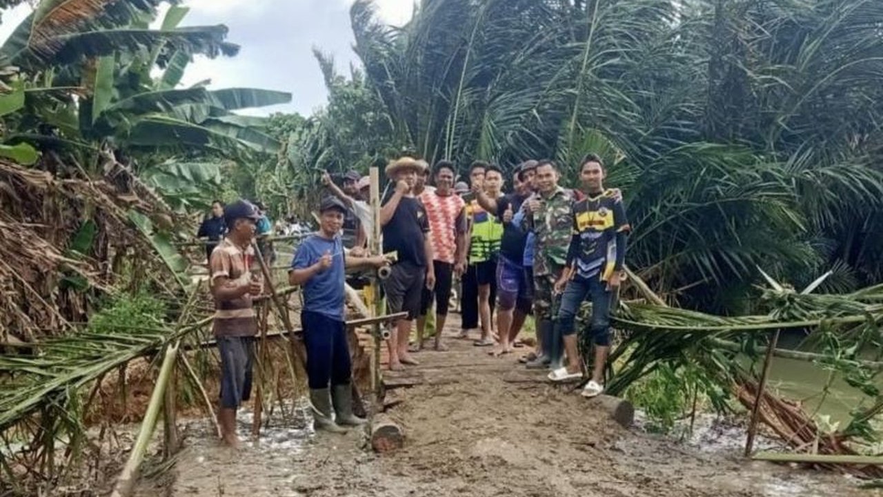 Akibat tanggul jebol di Desa Masiraan, Hulu Sungai Tengah, Kalimantan Selatan, TNI dan warga bergotong royong membangun jembatan darurat untuk akses warga yang terputus karena banjir.