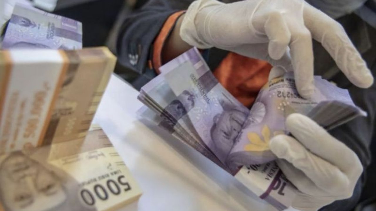 Pelemahan nilai tukar rupiah disebabkan oleh ekspektasi pasar bahwa The Fed tidak akan segera memangkas suku bunga, ditambah ancaman kenaikan tarif impor dari Presiden Trump yang berdampak negatif pada mata uang emerging market termasuk Indonesia.