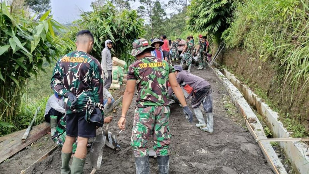 Pengerjaan pengecoran jalan dalam program TMMD di Desa Wonolelo, Magelang tetap berlanjut di bulan Ramadhan, menunjukkan semangat gotong royong TNI dan warga.