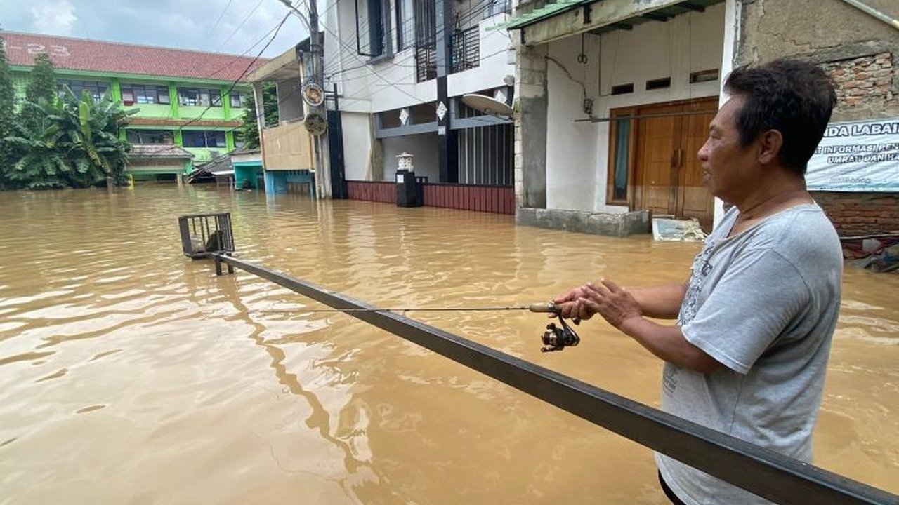 Banjir di Jakarta Selatan akibat meluapnya Kali Ciliwung menyebabkan warga terpaksa mengungsi dan sebagian lainnya memilih mengisi waktu dengan memancing di depan sekolah yang terendam.
