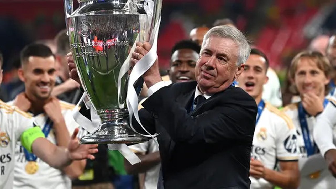 Carlo Ancelotti dan para pemain Real Madrid mengangkat trofi Liga Champions 2023/2024, Minggu (2/6/2024) dini hari WIB. (GLYN KIRK / AFP)