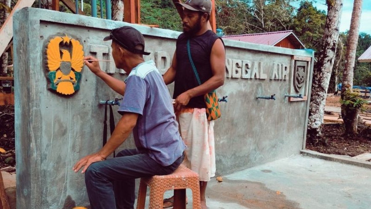 Satgas TMMD Ke-123 Kodim 1708/BN mengukir logo Kartika Eka Paksi di tugu sarana air bersih Kampung Kbusdori, Biak Numfor, Papua, sebagai simbol kebersamaan TNI dan rakyat.