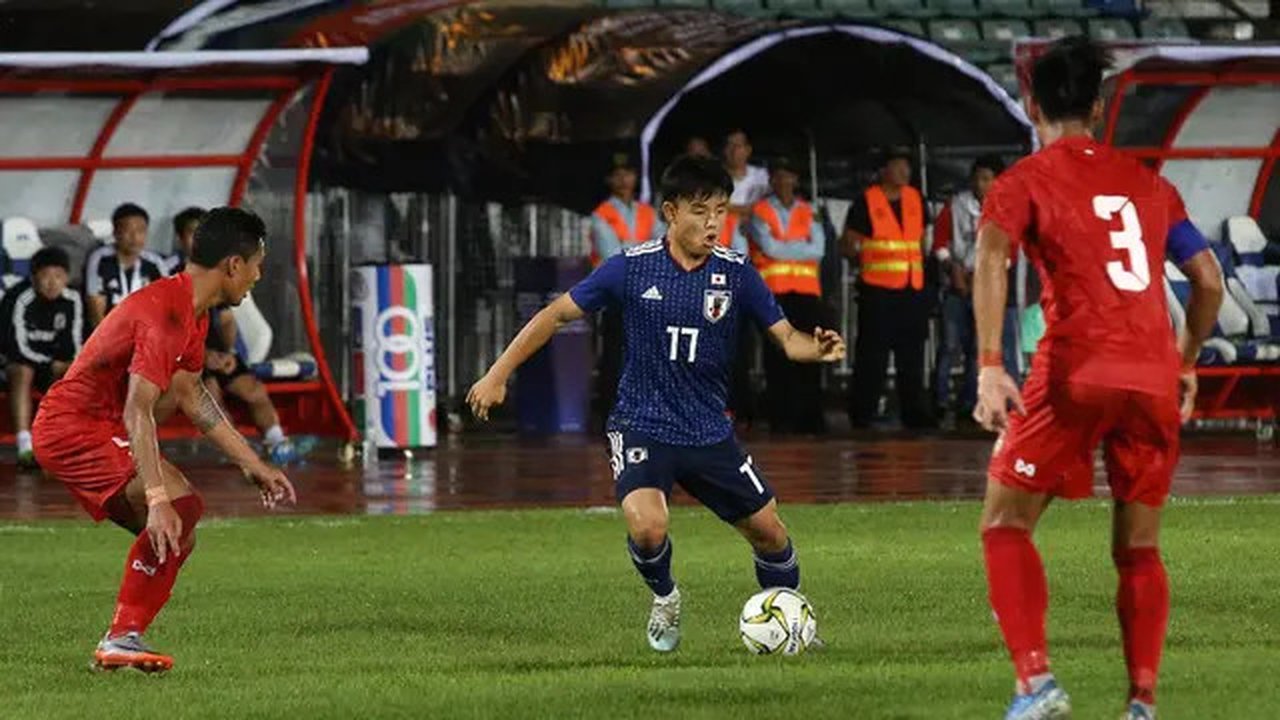 Dua pemain Timnas Myanmar saat mengadang pergerakan pemain Timnas Jepang, Takefusa Kubo, dalam matchday kedua Grup F kualifikasi Piala Dunia 2022 di Stadion Thuwunna, Yangon (10/9/2019). (AFP
