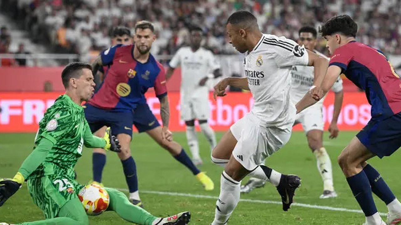 Kiper Barcelona, Wojciech Szczsny (kiri) menghalau bola tendangan pemain Real Madrid, Kylian Mbappe dalam laga final Copa Del Rey di La Cartuja stadium, Sevilla, Spanyol. (AFP/Josep Lago)