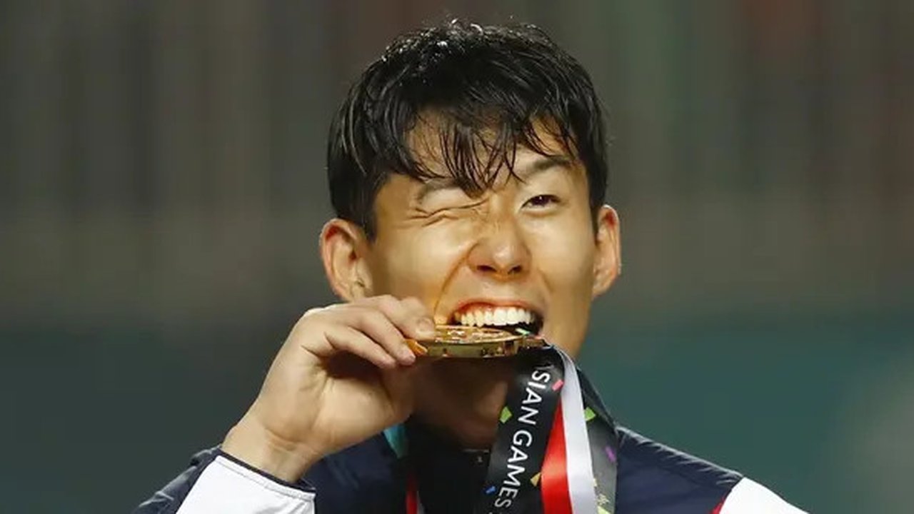 Penyerang Korea Selatan, Son Heung-min, menggigit mendali, usai menjuarai Asian Games dengan mengalahkan Jepang di Stadion Pakansari, Jawa Barat, Sabtu (1/9/2018). (AP/Bernat Armangue)