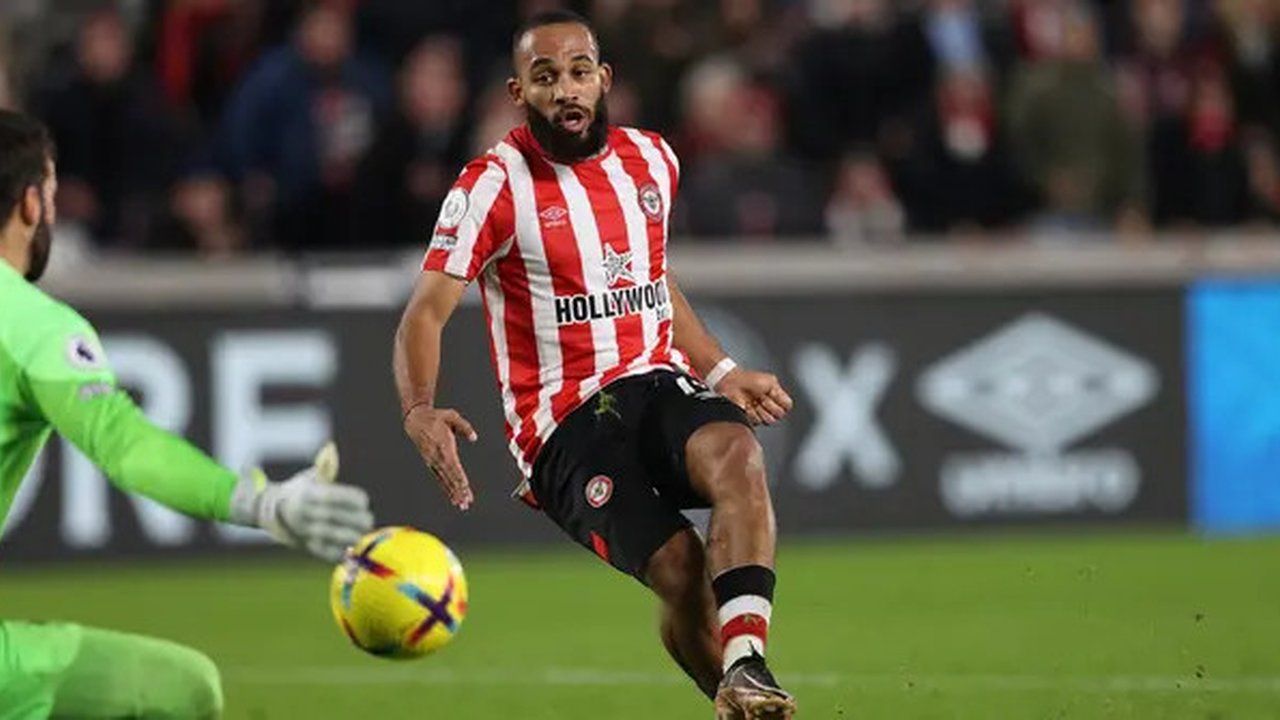 Striker Brentford, Bryan Mbeumo mencetak gol ke gawang Liverpool yang dijaga Alisson Becker pada laga Liga Inggris 2022/2023 di Gtech Community Stadium, London (2/1/2023). Bryan Mbeumo tampil