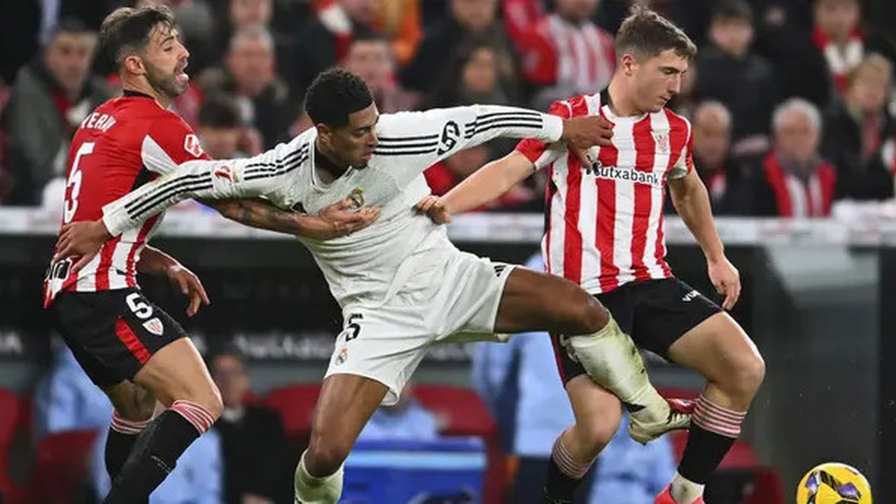 Pemain Real Madrid, Jude Bellingham berebut bola dengan pemain Athletic Bilbao, Mikel Jauregizar (kanan) dan Yeray Alvarez (kiri) pada laga lanjutan Liga Spanyol 2024/2025 di San Mames Stadiu