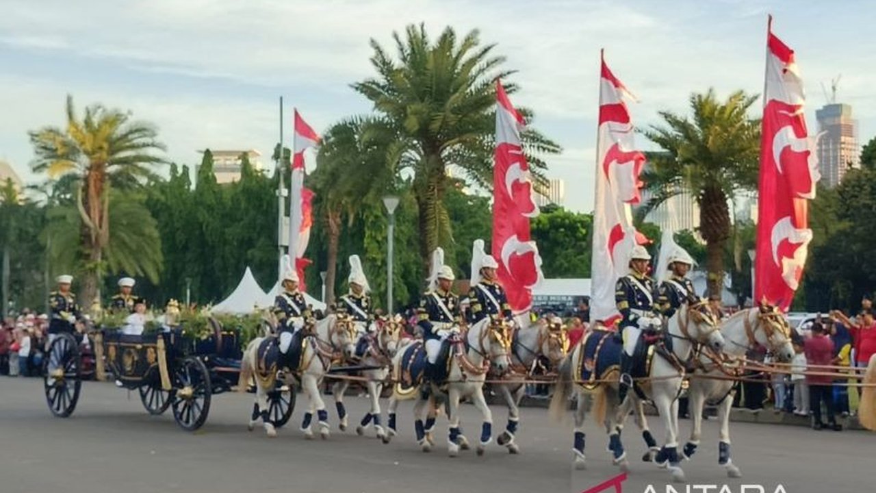 Masyarakat membanjiri kawasan Monas untuk menyaksikan langsung Kirab Penurunan Bendera HUT Ke-80 RI menggunakan kereta kencana, menciptakan momen bersejarah penuh antusiasme.