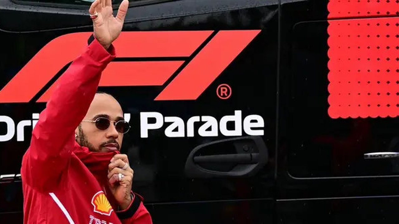 Pembalap Ferrari,  Lewis Hamilton, melambaikan tangan ke fans saat parade pembalap sebelum balapan F1 GP Inggris di Sirkuit Silverstone, Minggu (6/7/2025). (AFP/Ben Stansal)