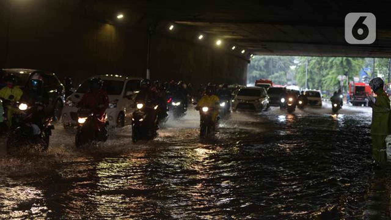 Pengendara sepeda motor menerjang banjir yang merendam terowongan di Cawang, Jakarta, Jumat (19/2/2021). Hujan yang turun sejak semalam membuat sejumlah jalanan di Ibu Kota tergenang banjir d