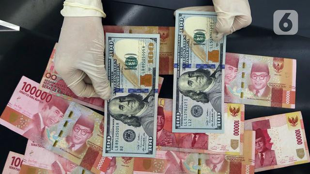 Karyawan menunjukkan uang dolar AS dan rupiah di Jakarta, Rabu (30/12/2020). Nilai tukar rupiah di pasar spot ditutup menguat 80 poin atau 0,57 persen ke level Rp 14.050 per dolar AS. (Liputa