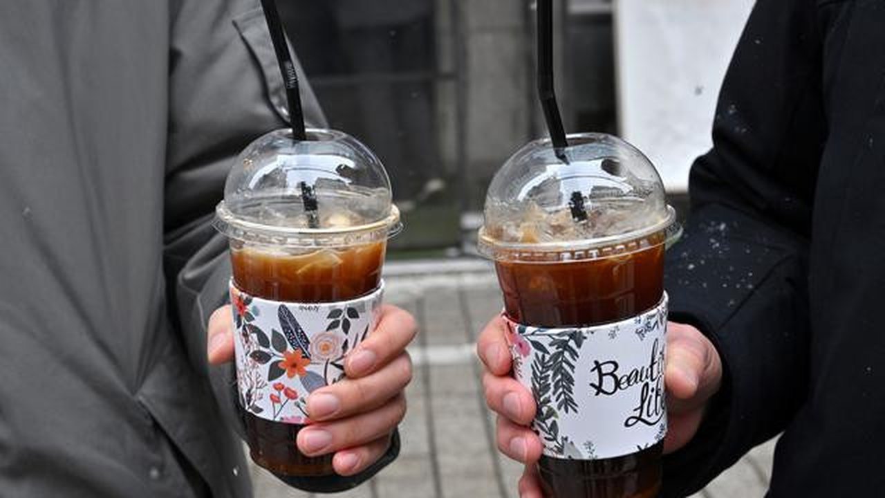 Gambar pada 26 Januari 2023 ini menunjukkan orang-orang memegang es Americano selama wawancara dengan AFP di sebuah jalan di Seoul. Kopi sederhana -- segelas espresso yang disajikan di ata