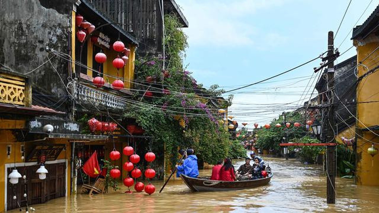Orang-orang menyusuri jalan yang terendam banjir dengan perahu setelah hujan deras di Hoi An, Vietnam, Kamis 30 Oktober 2025. Sedikitnya sembilan orang tewas dan lima lainnya masih dinyatakan