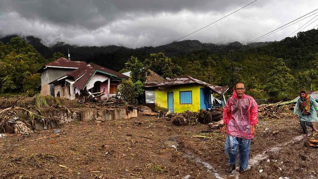Warga berjalan melewati rumah-rumah yang rusak di sebuah desa yang terdampak banjir di Malalak, Sumatera Barat, Jumat 28 November 2025. Jelang akhir November 2025, bencana banjir bandang dan