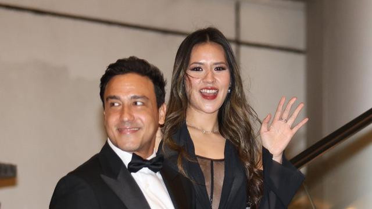 Raisa memilih maxi dress hitam dengan detail sheer v-neck yang memberi kesan ringan dan romantis. Hamish Daud melengkapi look sang istri dengan jas hitam andalannya, membuktikan kalau gaya fo