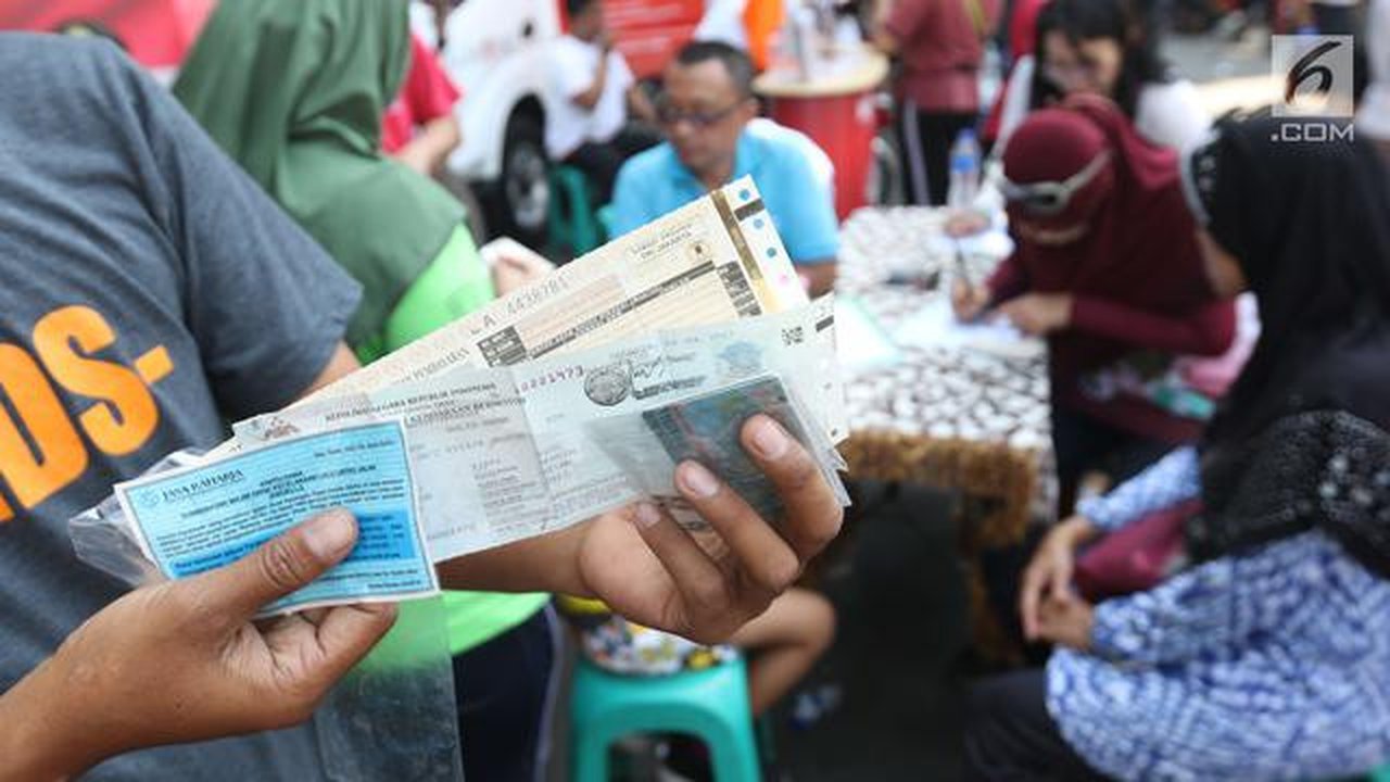 Warga menunjukkan STNK yang baru diperpanjang di gerai Samsat Keliling Car Free Day, Jakarta, Minggu (21/10). Layanan pembayaran pajak Surat Tanda Nomor Kendaraan (STNK) bisa dilakukan tanpa