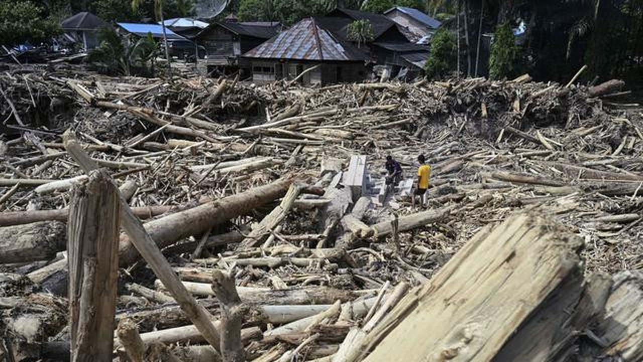 Warga desa memotong kayu-kayu yang hanyut oleh banjir bandang di Garoga, Provinsi Sumatera Utara, pada Kamis 4 Desember 2025. Banjir bandang di Desa Aek Garoga, Kecamatan Batang Toru, Tapanul