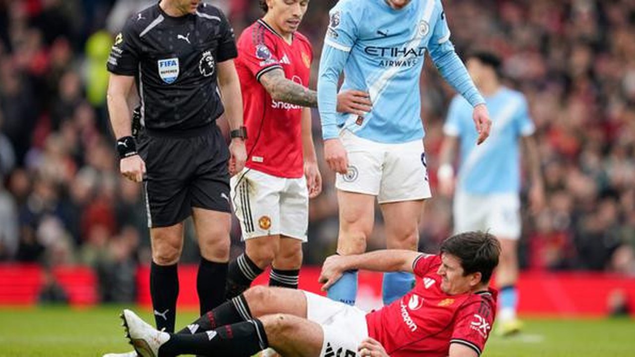 Harry Maguire dari Manchester United, di bagian bawah, tergeletak di lapangan kesakitan sementara wasit Anthony Taylor, Lisandro Martinez dari Manchester United, dan Erling Haaland dari Manch