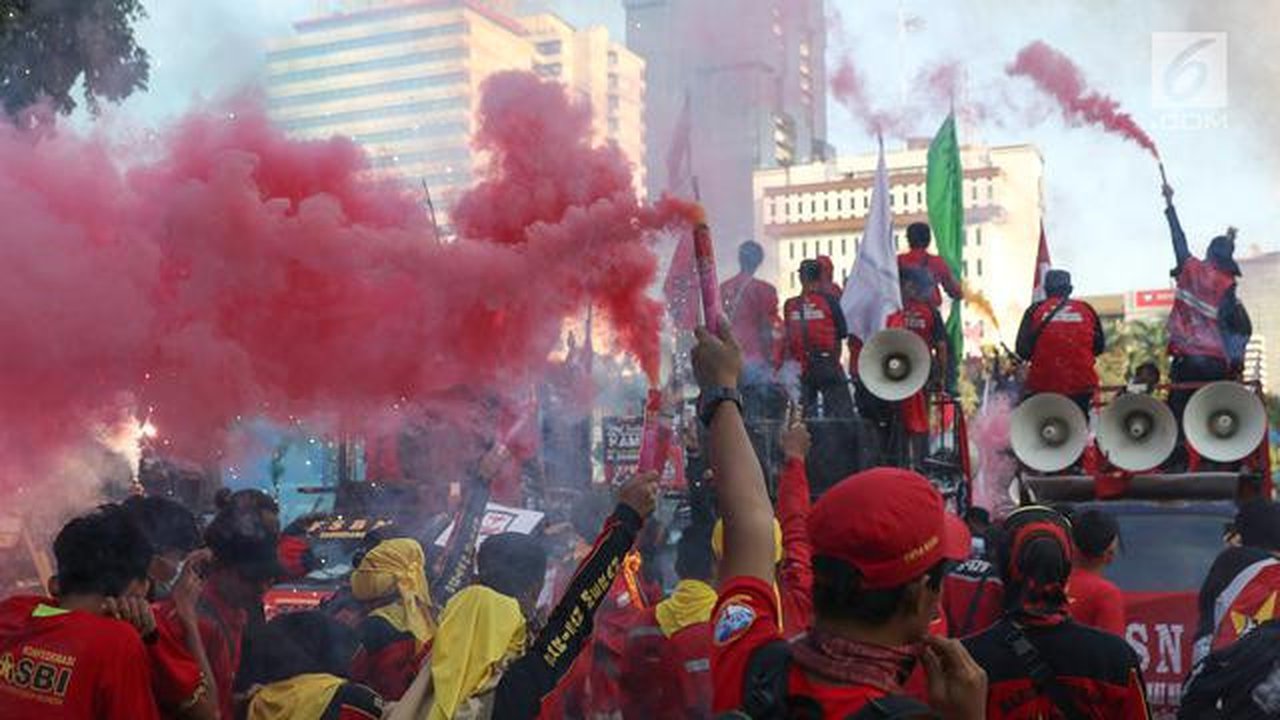 Sejumlah buruh menyalakan bom asap saat menutup aksi Hari Buruh Internasional di Jalan Medan Merdeka Barat, Jakarta, Rabu (5/1/2019). Aksi May Day 2019 di Jakarta ditutup oleh buruh dengan me