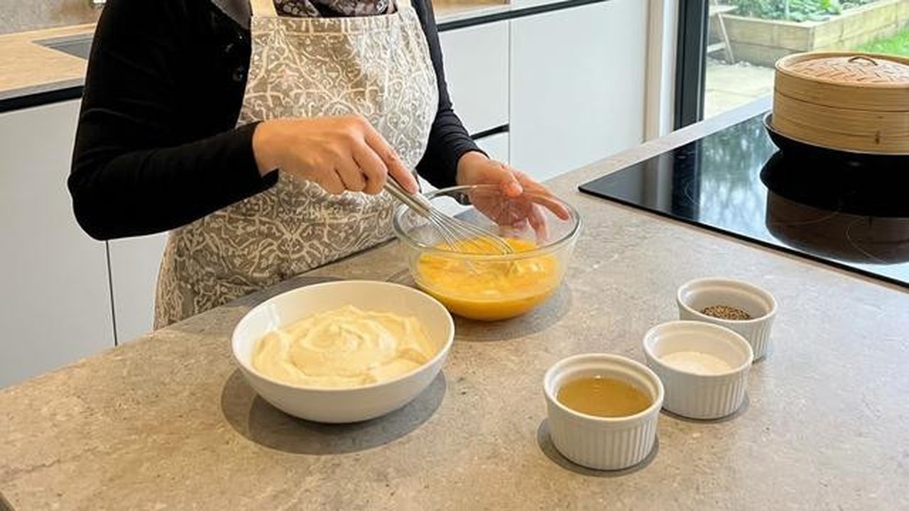 Mengocok telur merupakan salah satu tahapan memasak dengan resep telur tahu kukus lembut (Gemini AI)