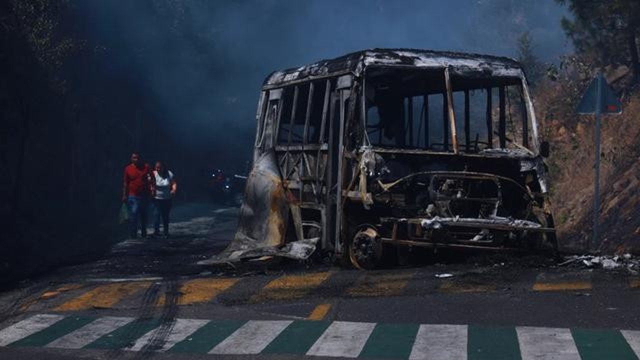 Warga berjalan melewati kendaraan yang hangus terbakar di sebuah jalan di Cointzio, Negara Bagian Michoacan, Meksiko, Minggu, (22/2/2026). Kendaraan tersebut dibakar menyusul tewasnya pemimpi