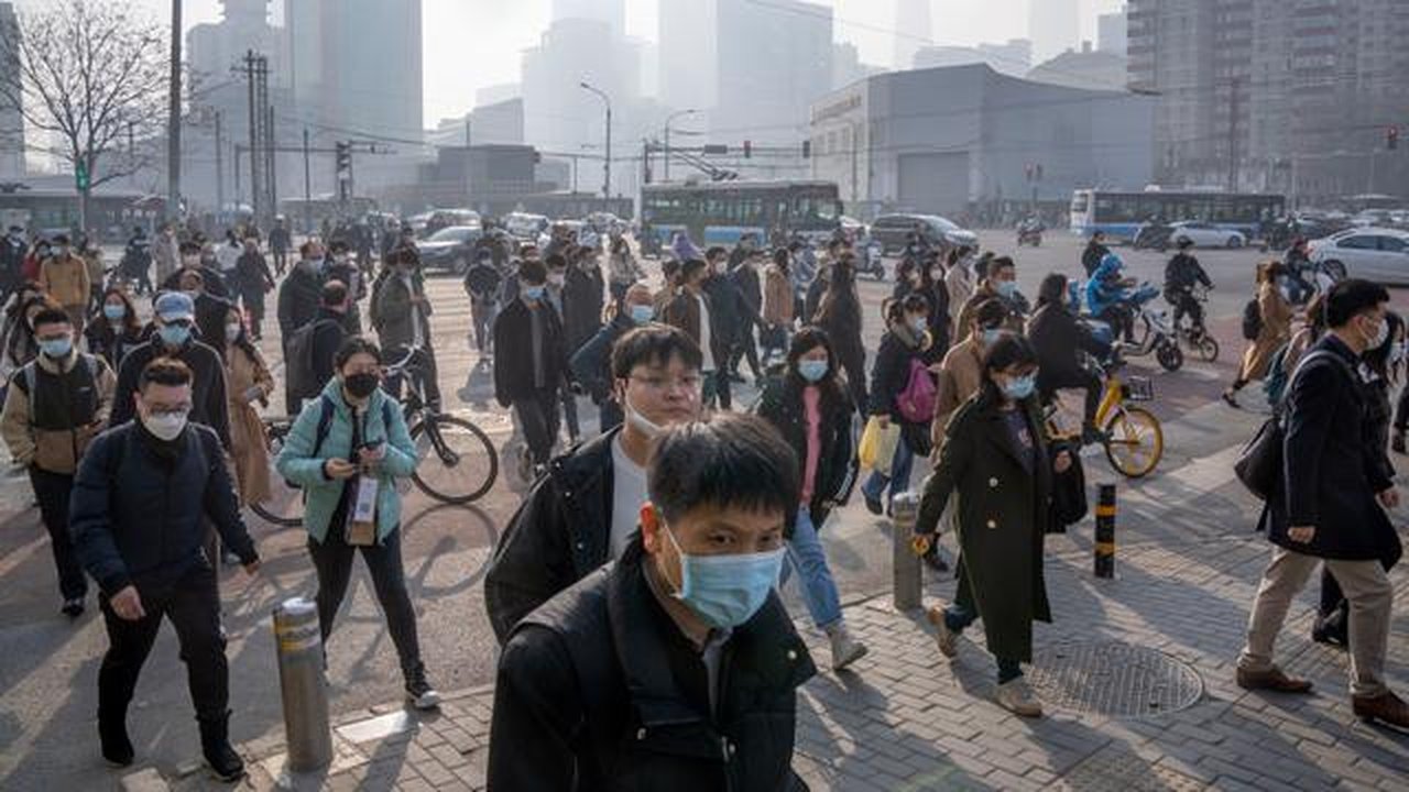 Komuter yang memakai masker berjalan melintasi persimpangan di kawasan pusat bisnis pada hari dengan tingkat polusi udara yang tinggi di Beijing, China, Senin (6/3/2023). Pejabat ekonomi Chin