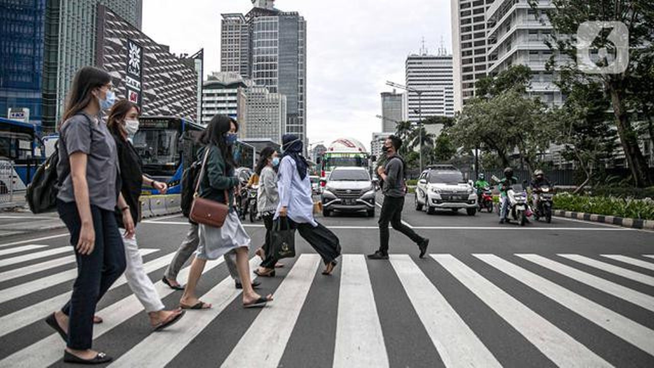 Orang-orang menyeberang jalan dengan latar belakang gedung perkantoran di kawasan Sudirman, Jakarta, Rabu (16/12/2020). Pemprov DKI Jakarta akan mengikuti arahan Wakil Ketua Komite Penanganan