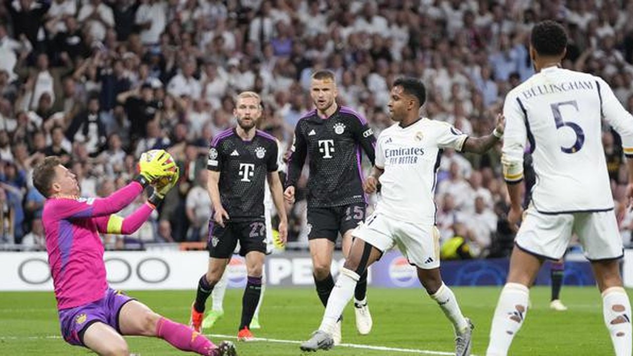Kiper Bayern Munchen, Manuel Neuer (kiri) berhasil menangkap bola tendangan striker Real Madrid, Rodrygo (tengah) pada laga leg kedua semifinal Liga Champions 2023/2024 di Santiago Bernabeu S