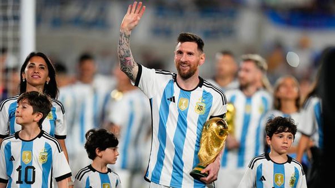 Lionel Messi berjalan ditemani Antonela Roccuzzo dan anak-anak mereka dengan membawa trofi Piala Dunia sambil menyapa para penonton. (AP Photo/Natacha Pisarenko)