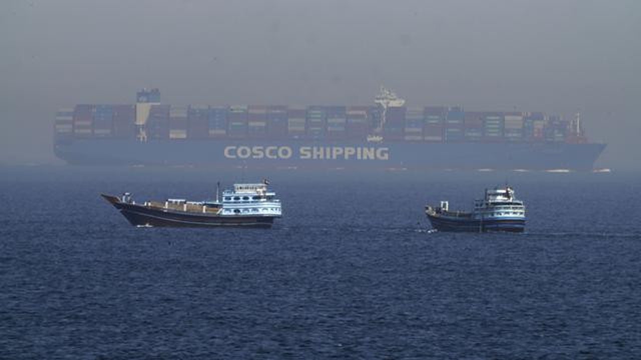 Dua perahu tradisional berlayar melewati sebuah kapal kontainer besar di Selat Hormuz, Jumat, 19 Mei 2023. (AP/Jon Gambrell)