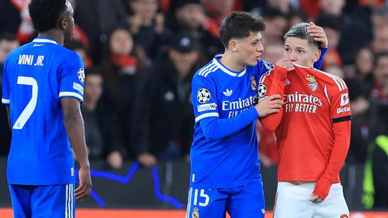 Vinicius Junior mencetak gol tunggal kemenangan Real Madrid atas Benfica pada laga leg pertama knockout play-off Liga Champions musim ini di Estadio da Luz, Lisbon, Rabu (18/02/2026) dini hari WIB. Sayangnya dalam duel tersebut, Vincius menjadi korban tindakan rasisme yang dilakukan pendukung dan pemain Benfica, Gianluca Prestianni (kanan).
