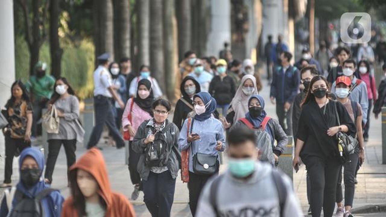 Pekerja melintas di trotoar Jalan Jenderal Sudirman saat jam pulang kantor, Selasa (4/1/2022). PPKM di Jakarta kembali diperpanjang oleh pemerintah pusat terhitung 4-17 Januari 2022 dari sebe