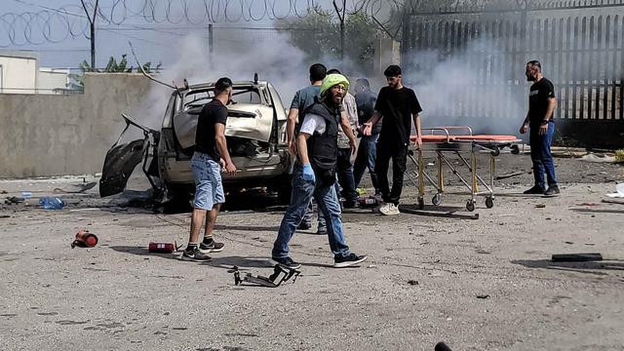 Petugas pertolongan pertama dan warga yang lewat berkumpul di sekitar reruntuhan kendaraan yang menjadi sasaran serangan pesawat tak berawak Israel di kota Jiyeh, Selatan Beirut, pada Rabu 13
