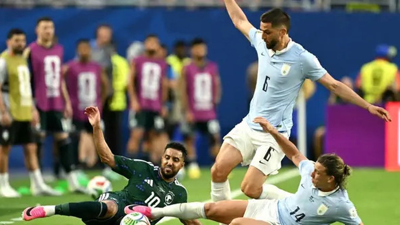 Penyerang Timna Arab Saudi, Salem Al-Dawsari, berebut bola dengan dua pemain Timnas Uruguay, Rodrigo Bentancur dan Agustin Canobbio, dalam laga pertama Grup H Piala Dunia 2026. Kedua tim berm