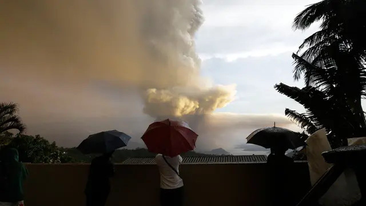 Sejumlah orang menyaksikan Gunung Api Taal erupsi di Tagaytay, Provinsi Cavite, Filipina, Minggu (12/1/2020). Gunung Api Taal mengeluarkan awan abu mencapai 50.000 kaki (15.000 meter) ke atmo