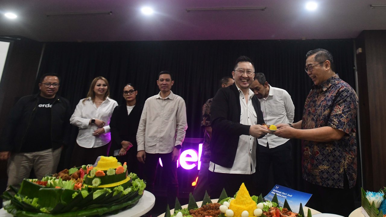 CEO Kapanlagi Universi (KLY) Danny Purnomo (kanan) menyerahkan nasi tumpeng kepada Corporate Secretary SCMA, Gilang Iskandar saat ulang tahun ke 14 Merdeka.com di Gedung KLY, Jakarta, Senin (23/02/2026)