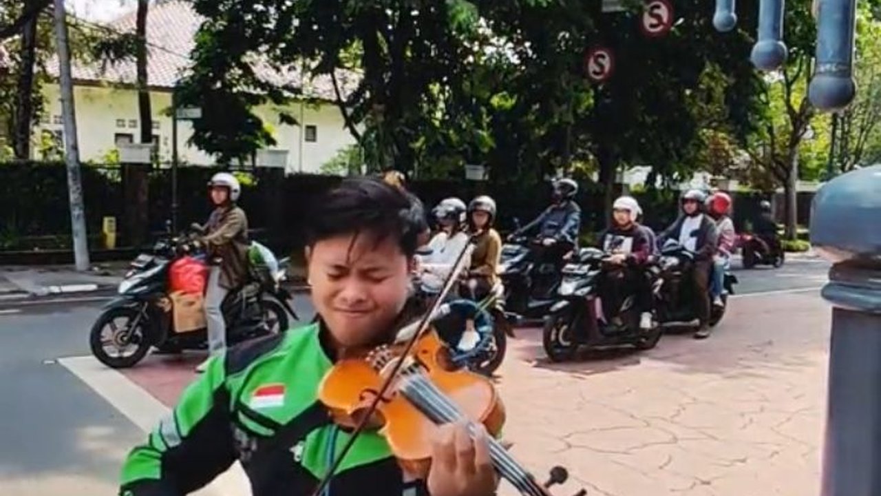 Aksi Pria Berjaket Ojol Main Biola di Lampu Merah Ini Viral, Keren Banget
